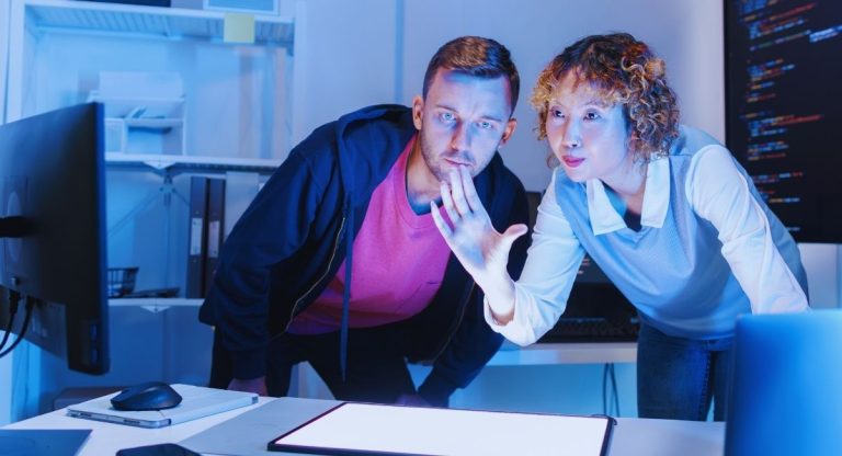 Deux developpeurs travaillent ensemble devant un ecran d'ordinateur affichant du code source