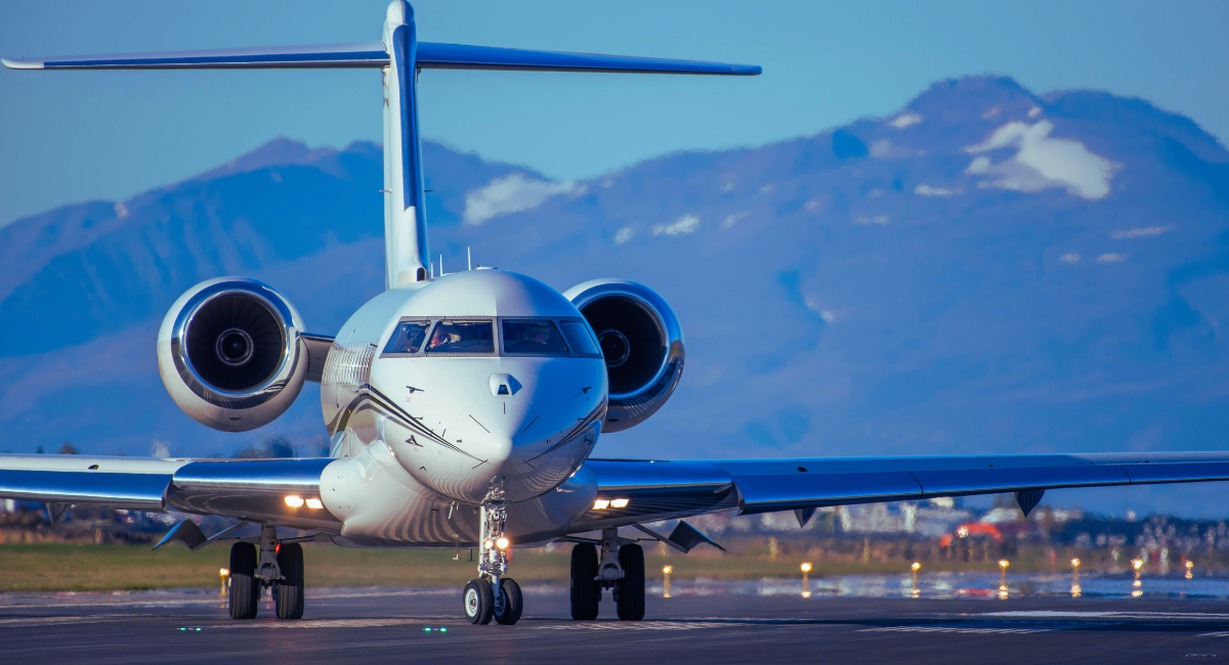 Jet privé sur piste d'aéroport avec vue montagne, symbole du patrimoine colossal des milliardaires comme Elon Musk