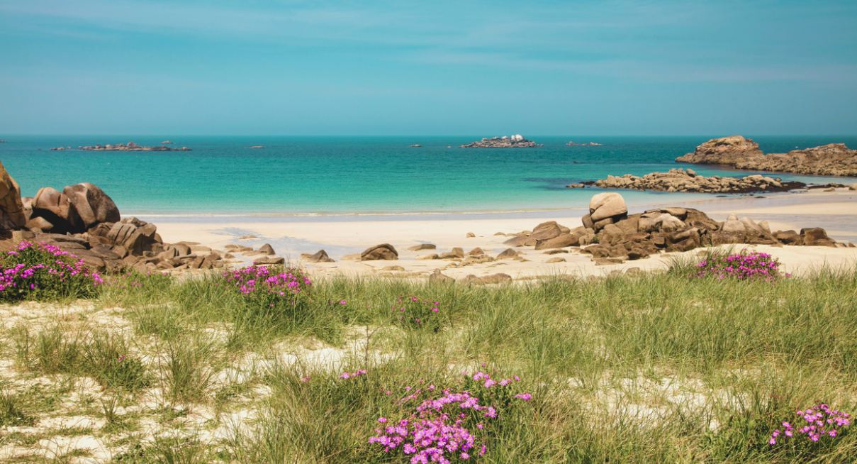Plage sauvage de Bretagne avec rochers de granite rose et mer turquoise sous ciel bleu