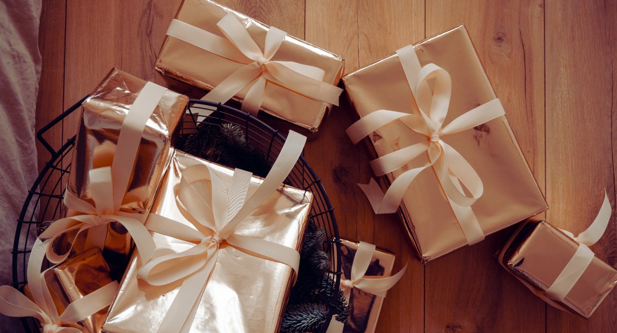 Assortiment de cadeaux d'entreprise emballes dans du papier dore avec des rubans sur un plan en bois