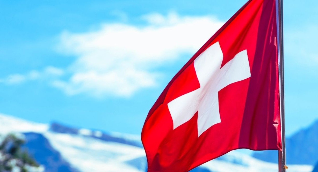 Drapeau suisse flottant au vent avec les Alpes enneigees en arriere-plan