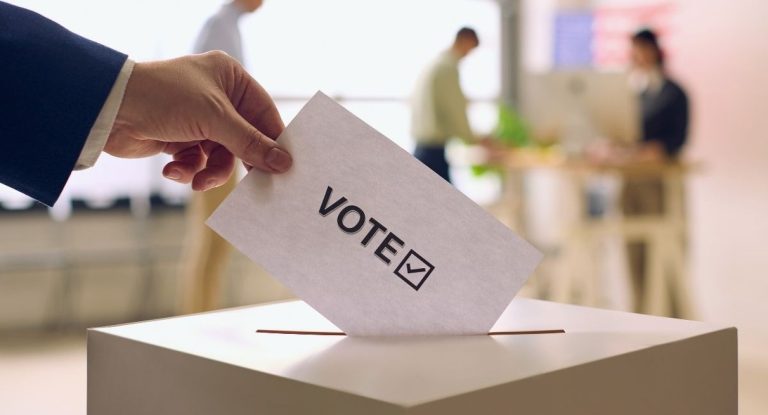 Main deposant une enveloppe de vote dans une urne electorale