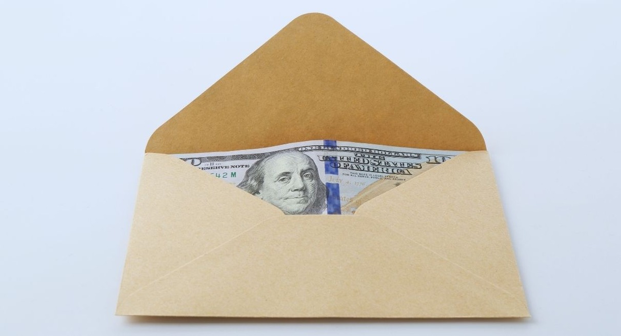 Enveloppe en papier kraft ouverte laissant apparaitre des billets de banque