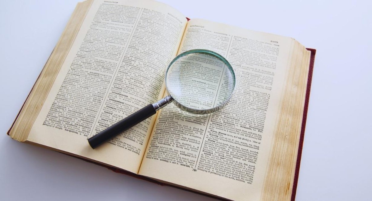 Loupe posee sur les pages d'un dictionnaire ouvert pour chercher une definition