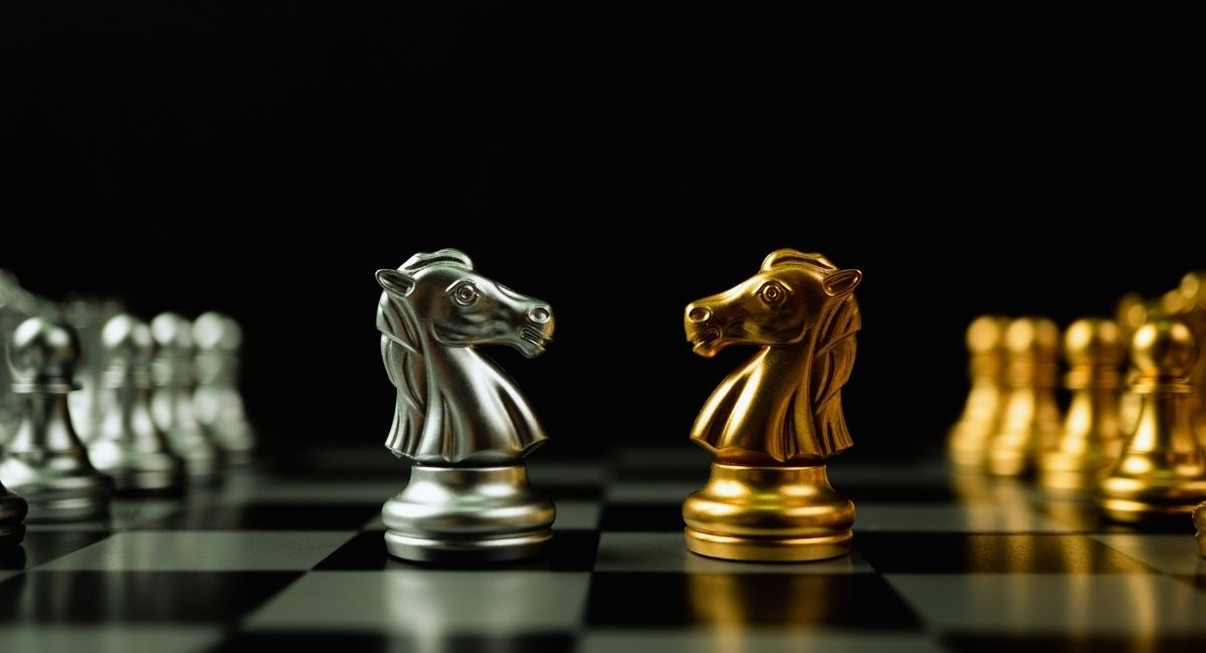 Deux cavaliers d'echecs dores et argentes places face a face sur un echiquier