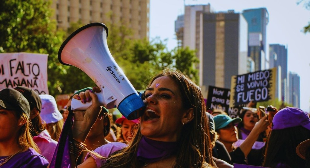 Une militante scande des slogans dans un mégaphone au milieu d'un cortège de manifestants brandissant des pancartes