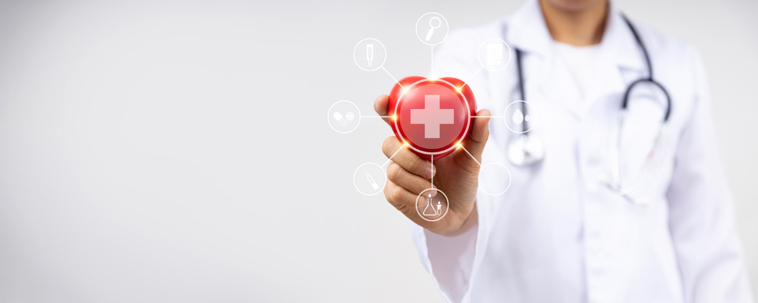 Un professionnel de la santé montre un coeur avec une croix médicale au centre afin de représenter le concept de mutuelle santé.